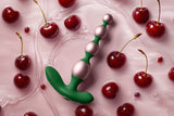 FemmeFunn bougie beads sitting in a shallow pool of water surrounded by cherries 