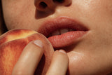Woman holding a peach to her mouth