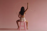 Woman sitting in pink room with a lasso above her head