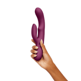 A hand holding the dark fuchsia FemmeFunn Balai rabbit vibrator.