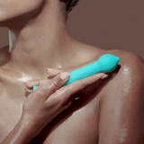 A model holding the FemmeFunn Diamond Wand in teal.
