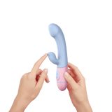 Two hands holding the light blue and pink FemmeFunn ffix Rabbit, showing the button placement on the handle.