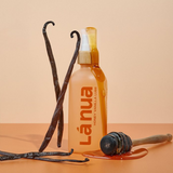 A lifestyle image showing a bottle of La Nua's Honey Vanilla lube with vanilla beans.