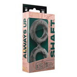 A gray silicone double cock ring shown in its dark green and black retail packaging, featuring "Shaft" branding.