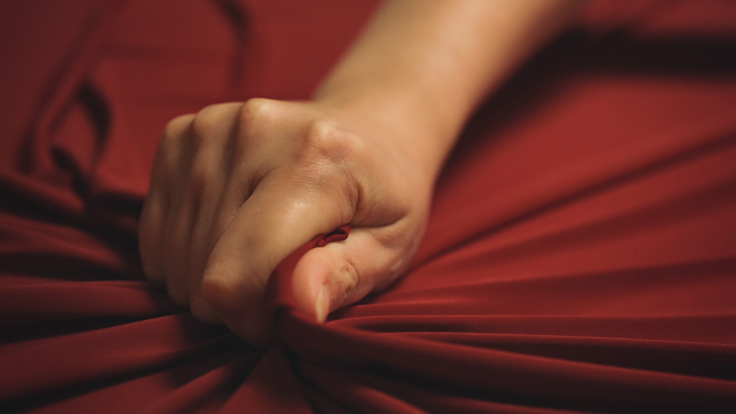 hand clenching red sheet