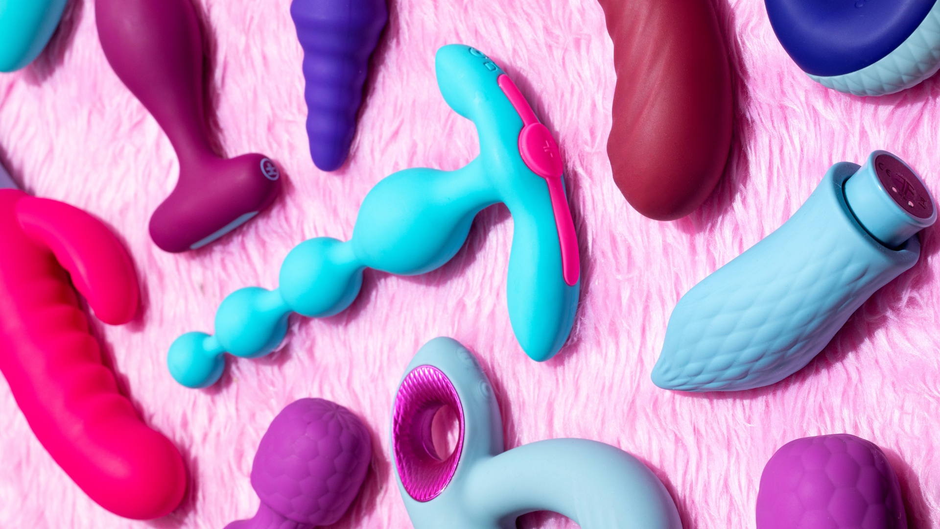 Femme funn sex toys against a pink background